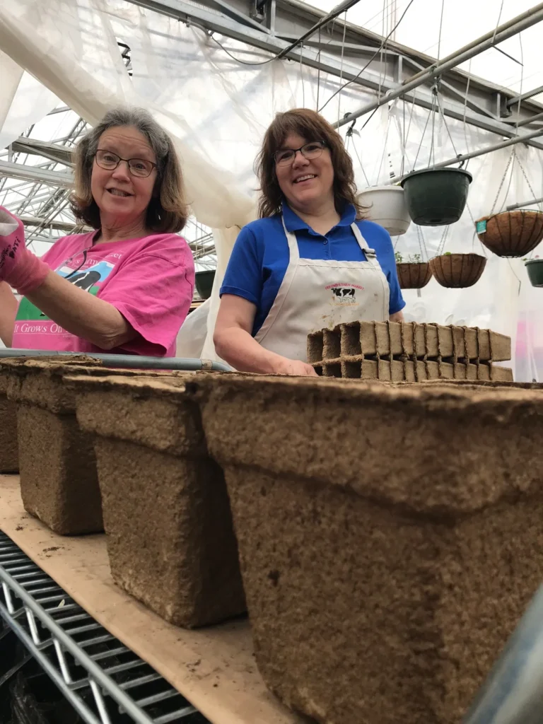 farmers filling large biodegradable pots with potting soil.