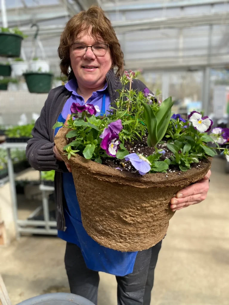 Theresa holds flowering spring annuals planted in a #17 Round cowpot