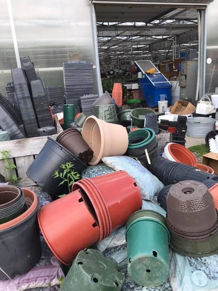 pile of plastic pots behind greenhouse 